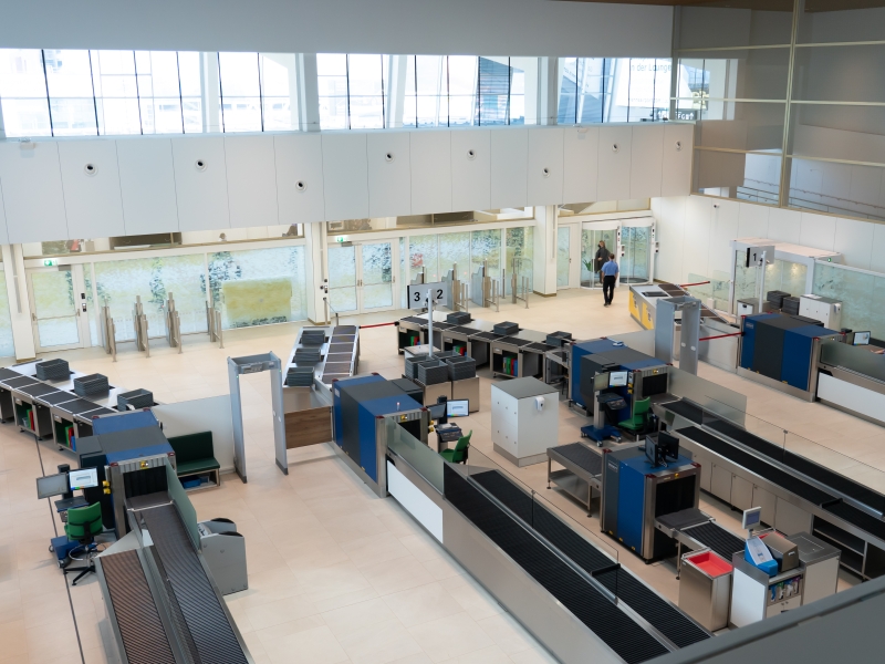 Gesamtaufnahme von Flughafen-SIKO: Von Gepäckabgabe über Personenschleuse bis hin zur Gepäckrückgabe nach Gepäckprüfung (rechts im Bild: Nachkontrollbereich inklusive Handschuhspender, Mülleinhausung und Arbeitsfläche für Prüfgeräte)